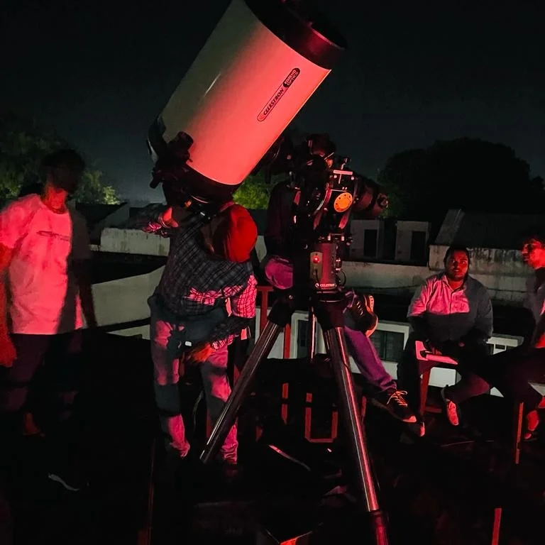 Two brothers, toddler boys, looking at the stars using a telescope by the sea on a beautiful summer night.